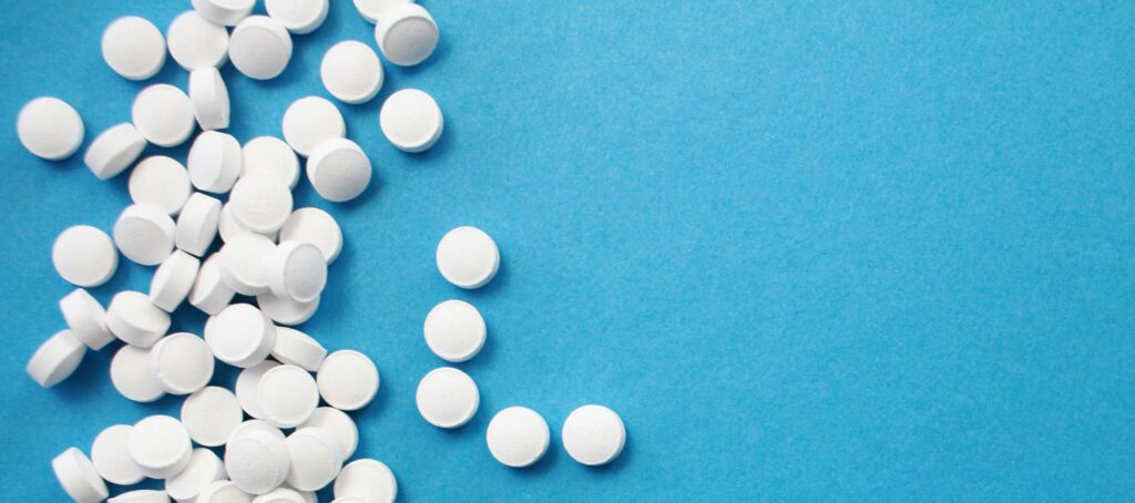 White pills lie scattered across a blue background.