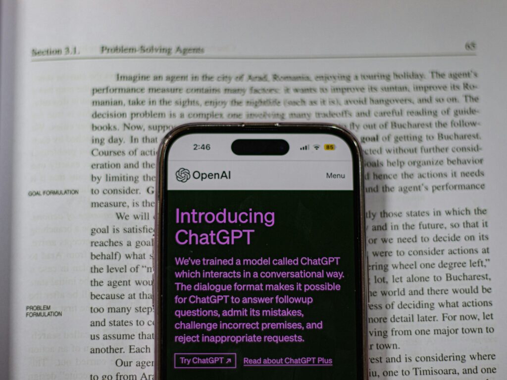 A smartphone shows the ChatGPT index page against a page of text.